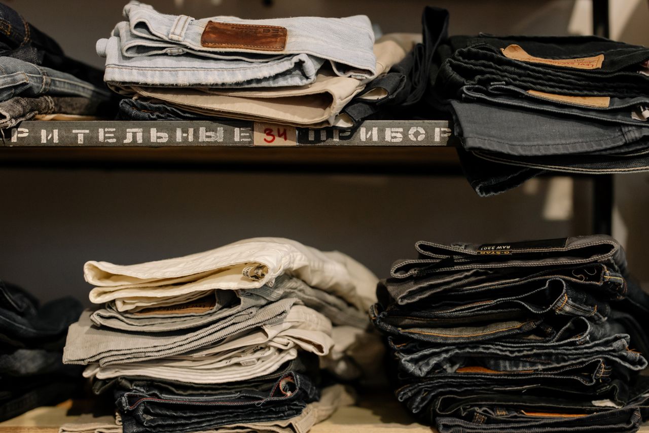 Folded jeans neatly stacked on shelves in a retail store, showcasing various styles and sizes.